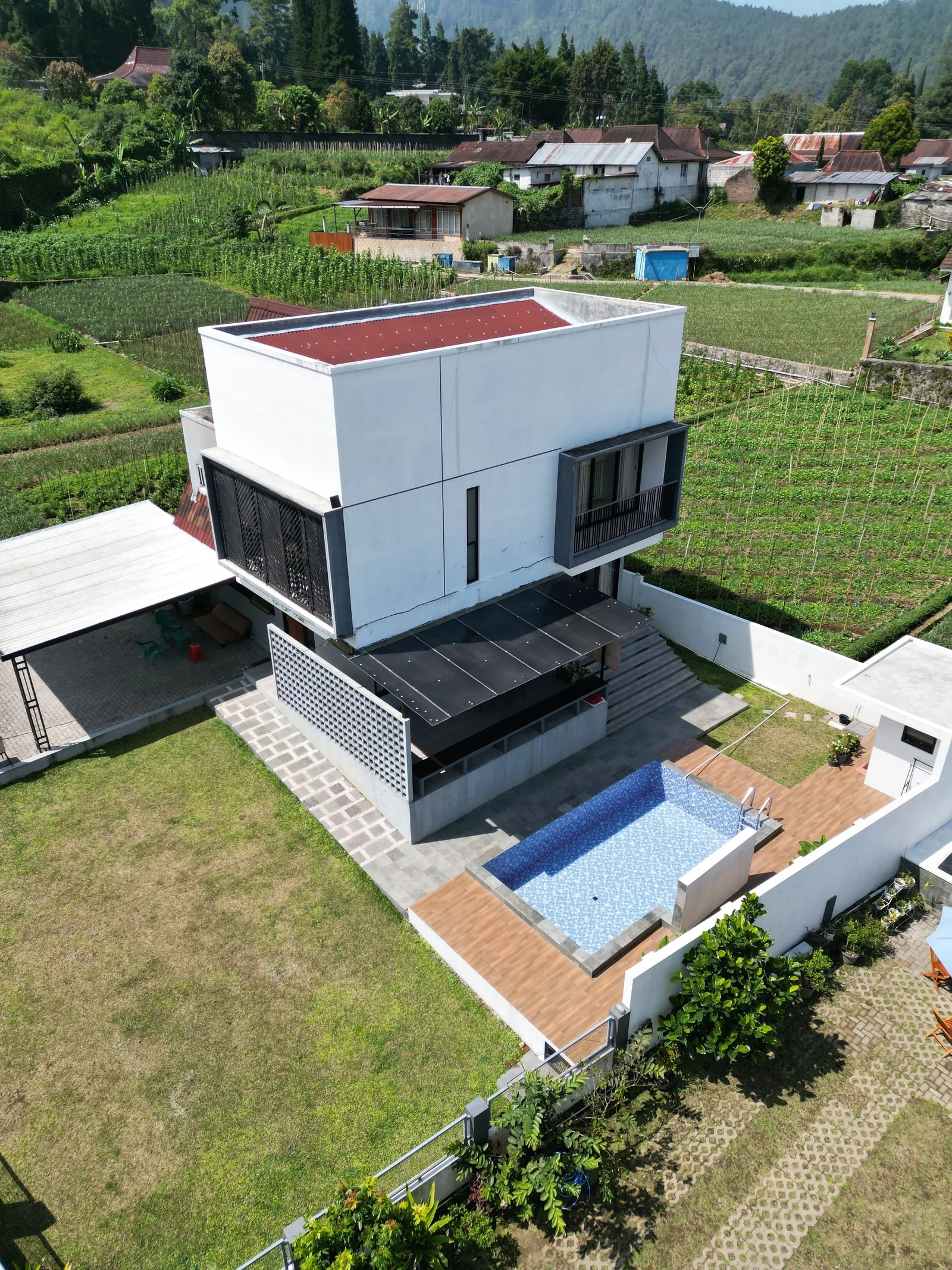 A white house on a green hillside seen from above