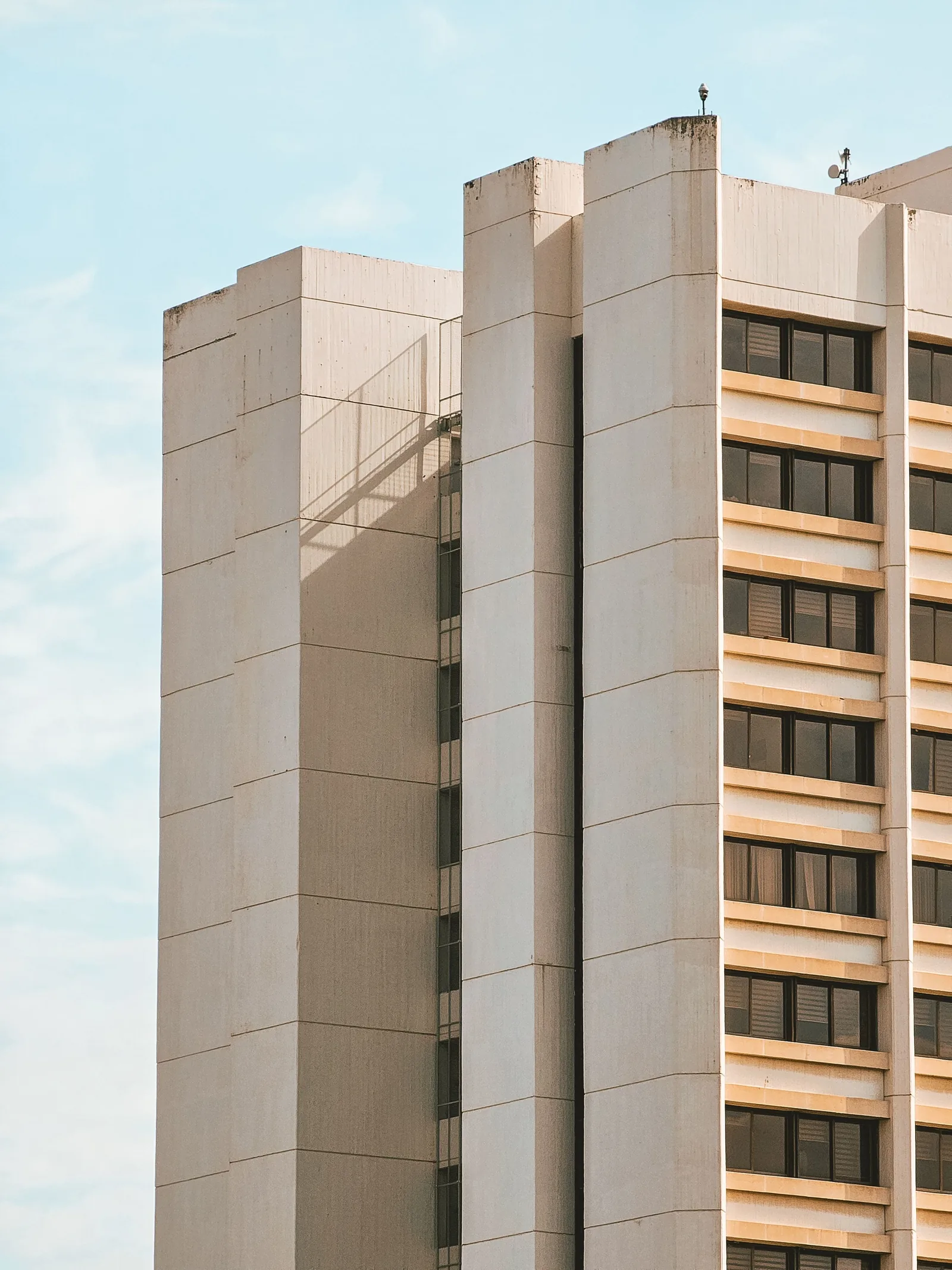 A pale concrete tower with deep window bays against an open sky