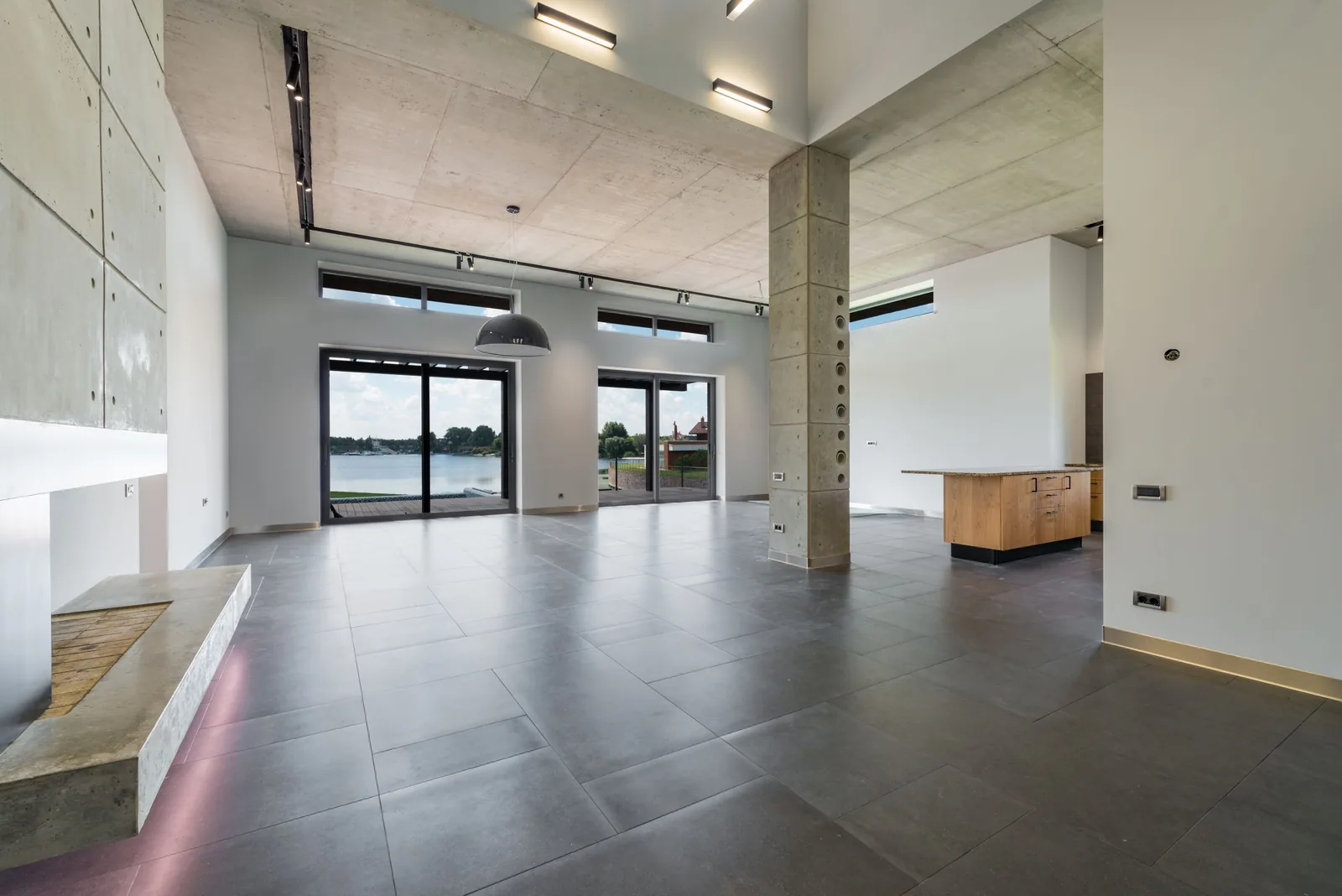 A wide open loft with grey floor tiles and a long window